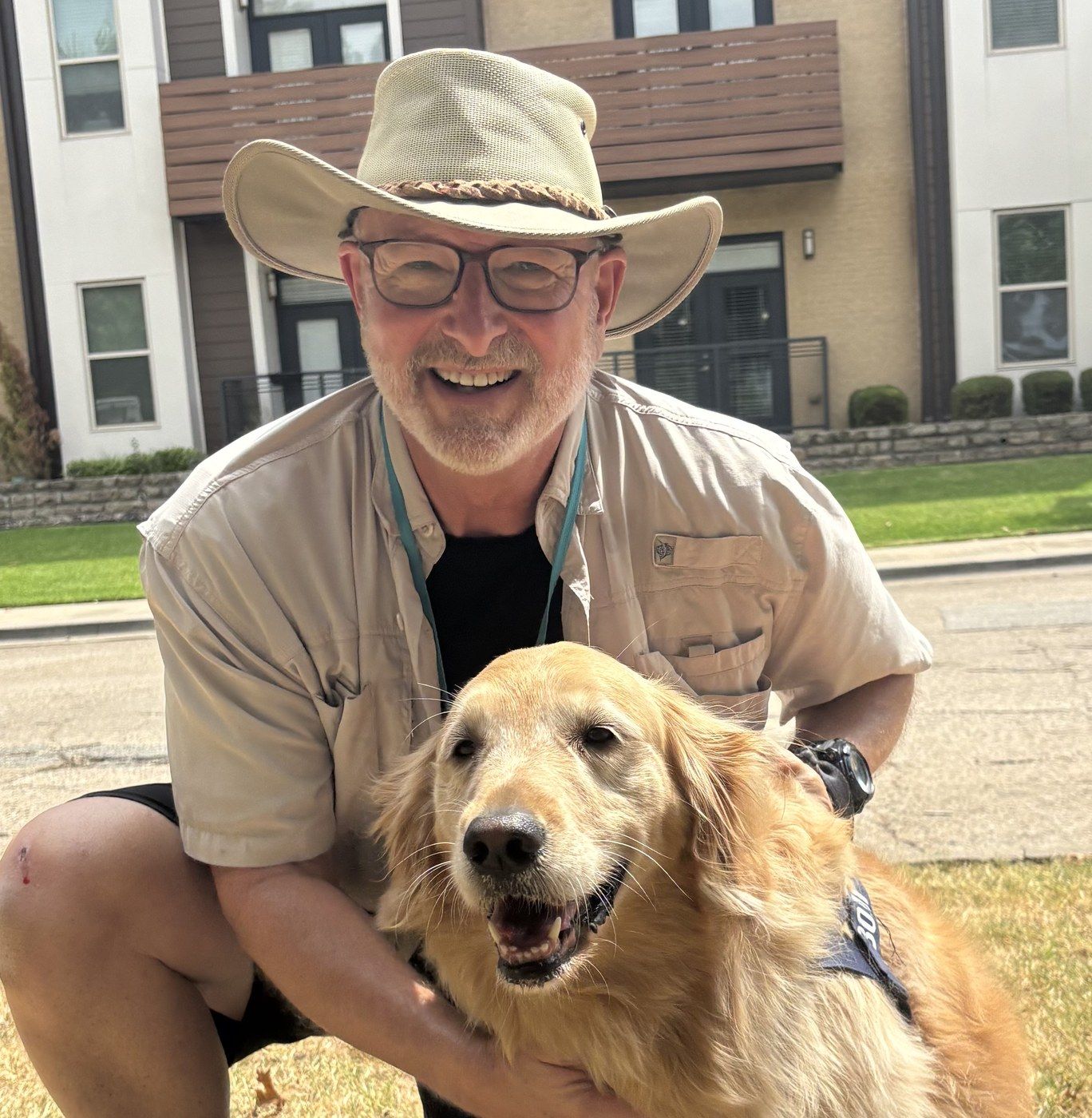 Steve kneeling on a neighborhood lawn with a smiling golden retriever